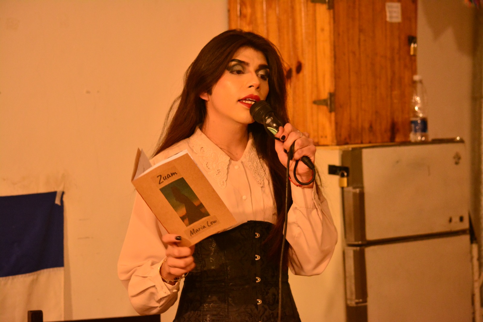 María Lew speaks into a microphone holding a book titled Zuam.