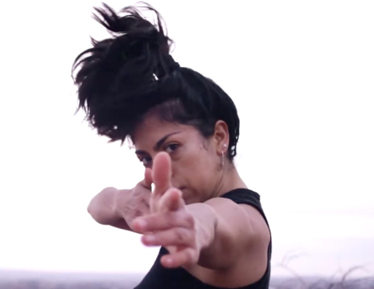Ayliñ poses during a dance with an arid landscape background.