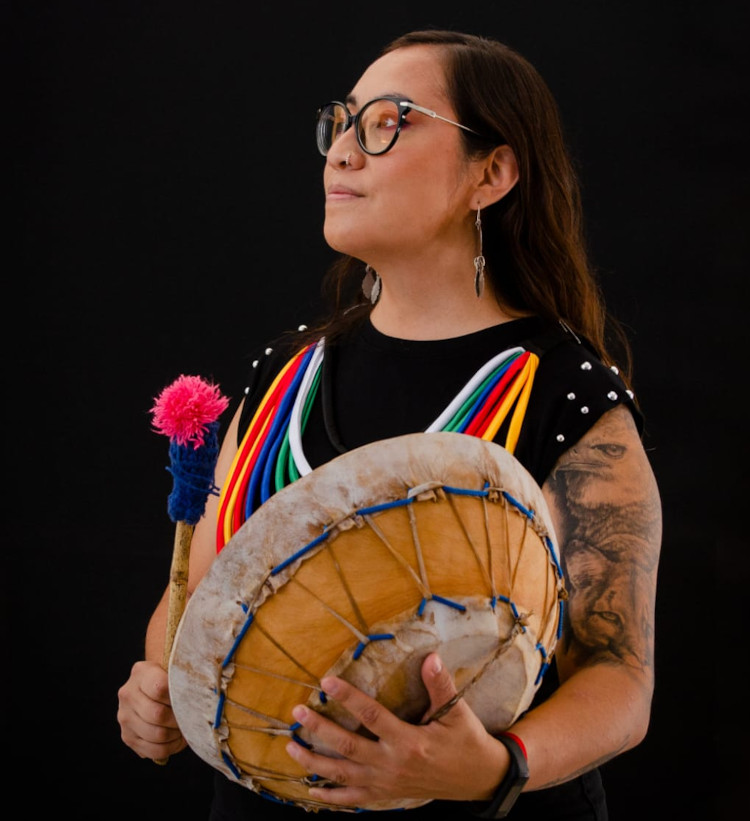 WeWay member holds a kultrun drum looking to the left.