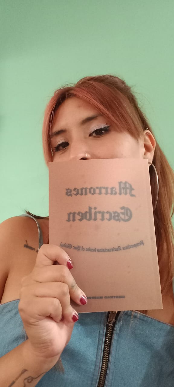 America Canela, one of the authors, shows her book against her skin.