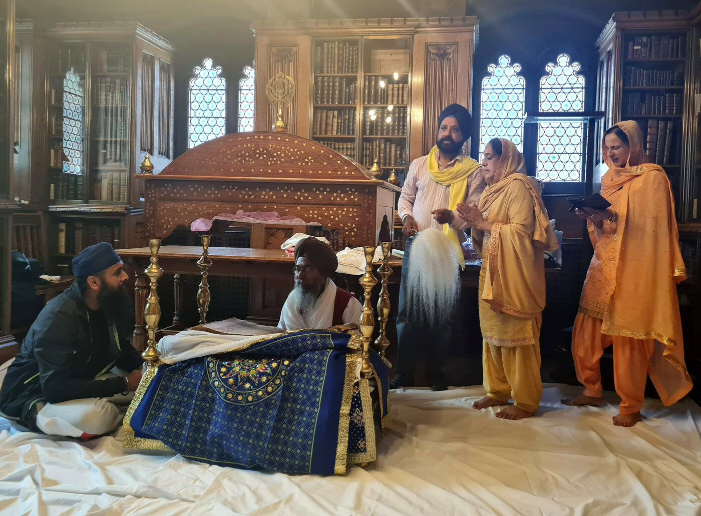 Five members of the Sikh community and religions leaders surround the Sri Guru Granth Sahib, seated in its palki.