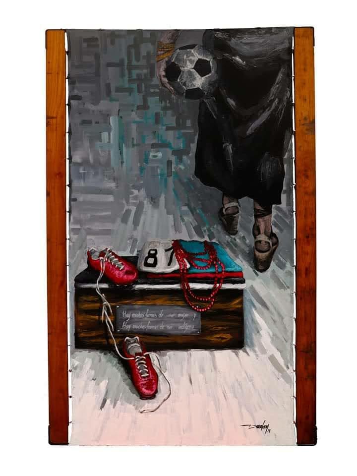 A football and worn shoes are carried by a person, in a room with a box holding cleats, a jersey, and red beads on a pale floor.