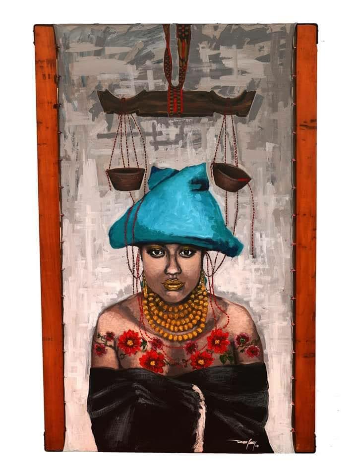 A figure wearing a blue head covering stands beneath hanging scales, dressed in floral patterns and layered beads.