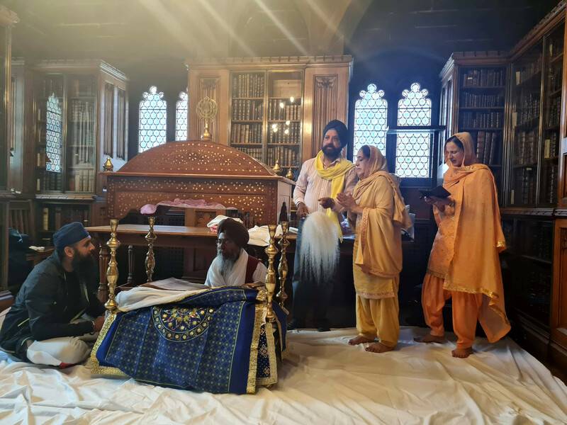 Five members of the Sikh community and religions leaders surround the Sri Guru Granth Sahib, seated in its palki.
